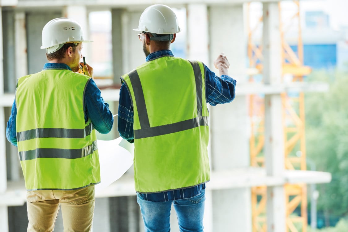 A manager and supervisor discussing building plans on a construction site.