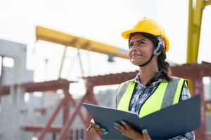 appointed person on construction site smiling and looking up at crane