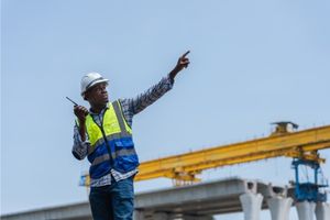 crane supervisor wearing hi-vis pointing at crane on-site