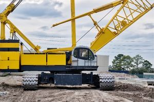 big yellow crawler crane on an active construction site